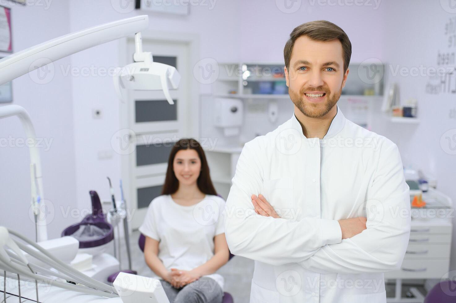 Male dentist in a room with medical equipment and patient on background. photo