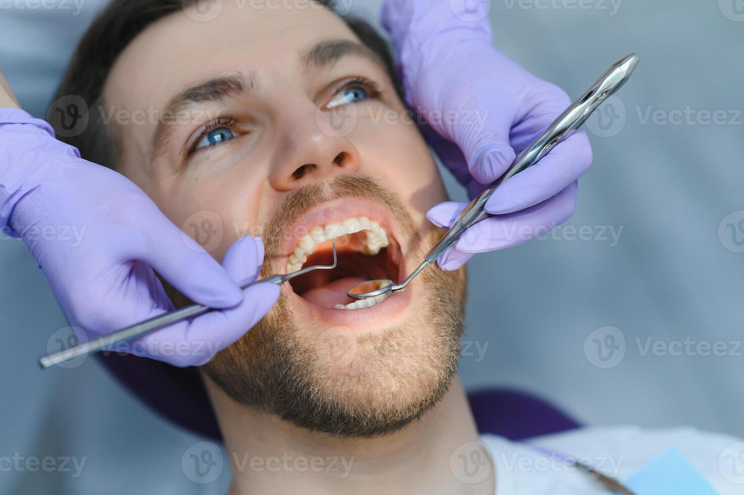 Periodontal Services. Closeup Shot Of Smiling Man Getting Treatment In Stomatologic Clinic, Dentist Doctor In Gloves Using Sterile Dental Tools For Examining Teeth Of Male Patient photo