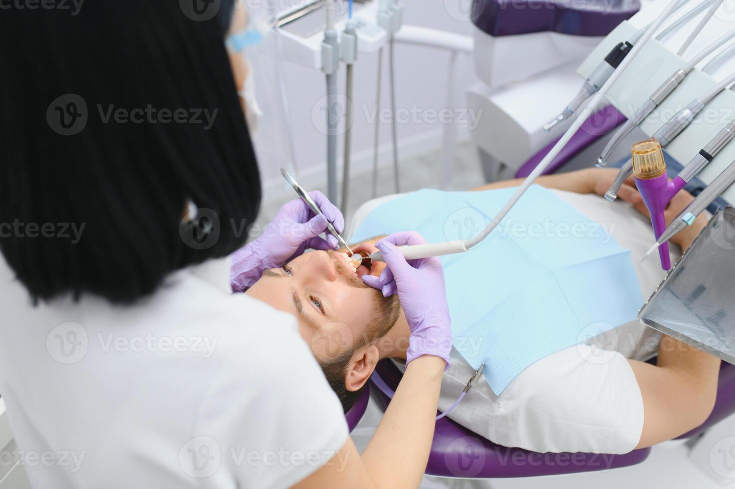 Man having a visit at the dentist's. Handsome patient sitting on chair at dentist office in dental clinic. photo