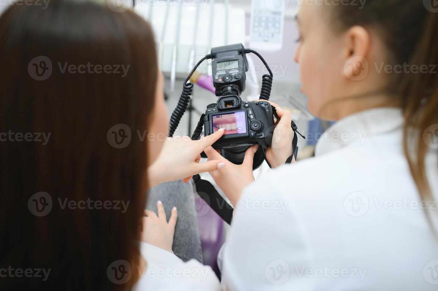 Female dentist photographs her patient's teeth in a dental chair. photo