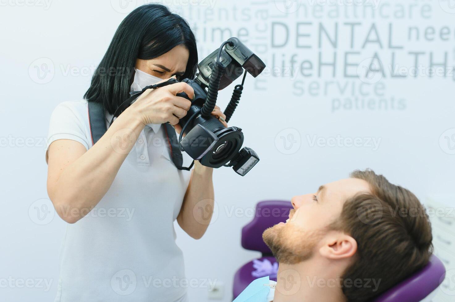Female dentist photographs her patient's teeth in a dental chair. photo
