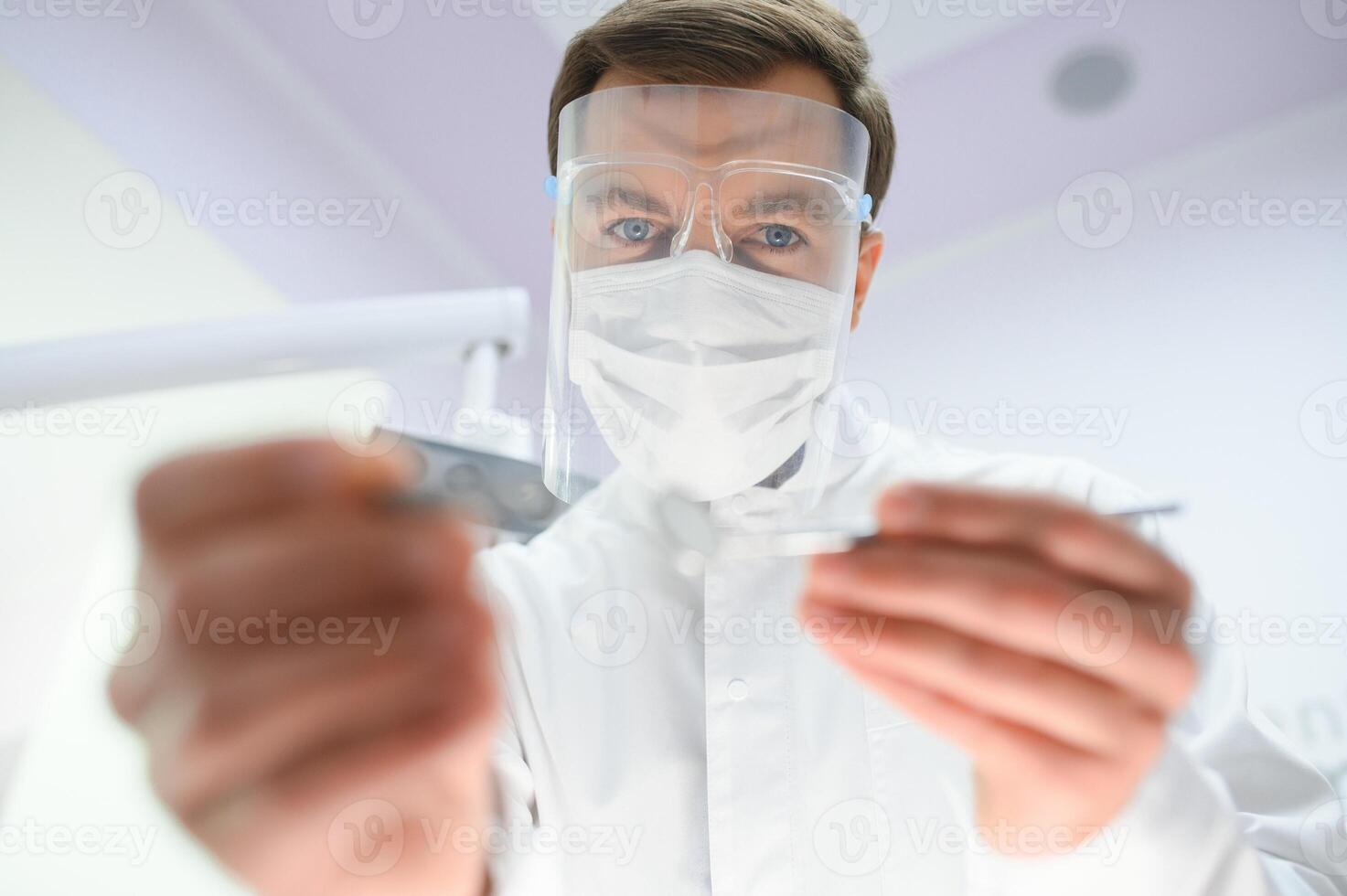 Bottom view. Dentist man with a tool in his hand. photo