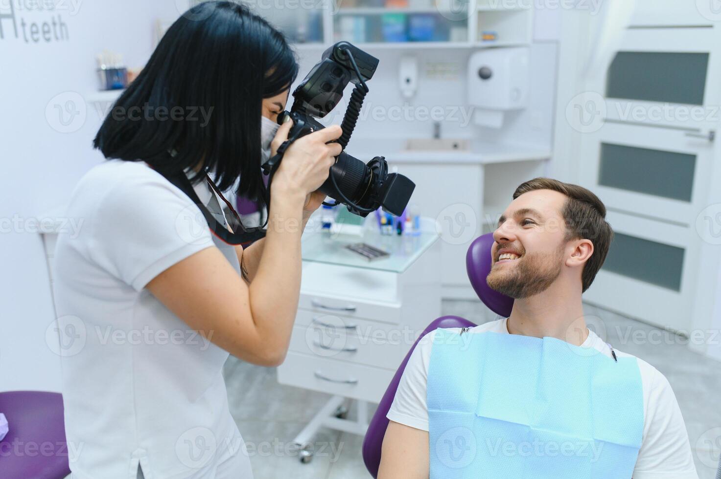 Handsome man smiling while teeth exam. Happy male patient sitting in a dentist's chair and having check up teeth. photo