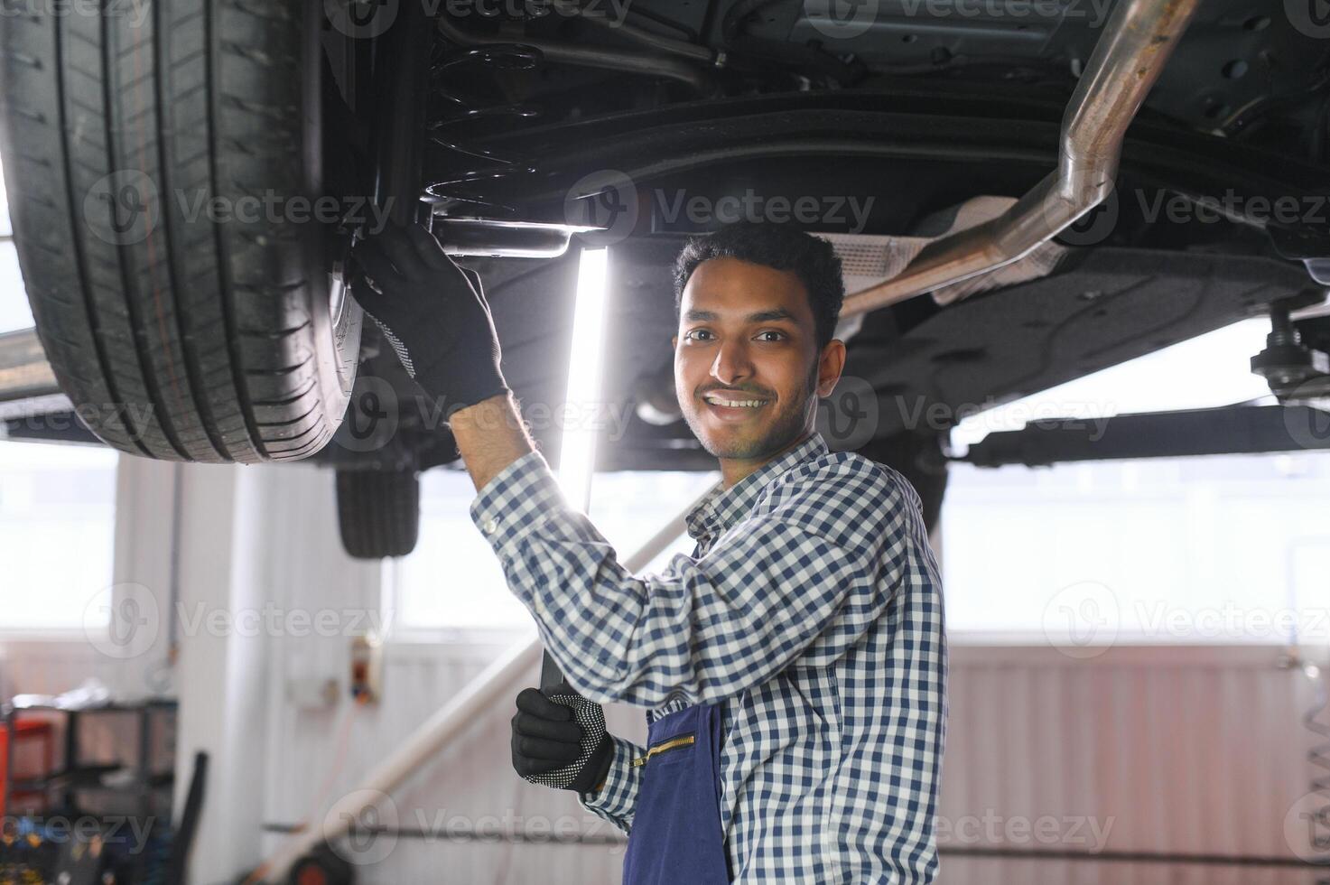 service, repair and profession concept - indian mechanic at car service photo