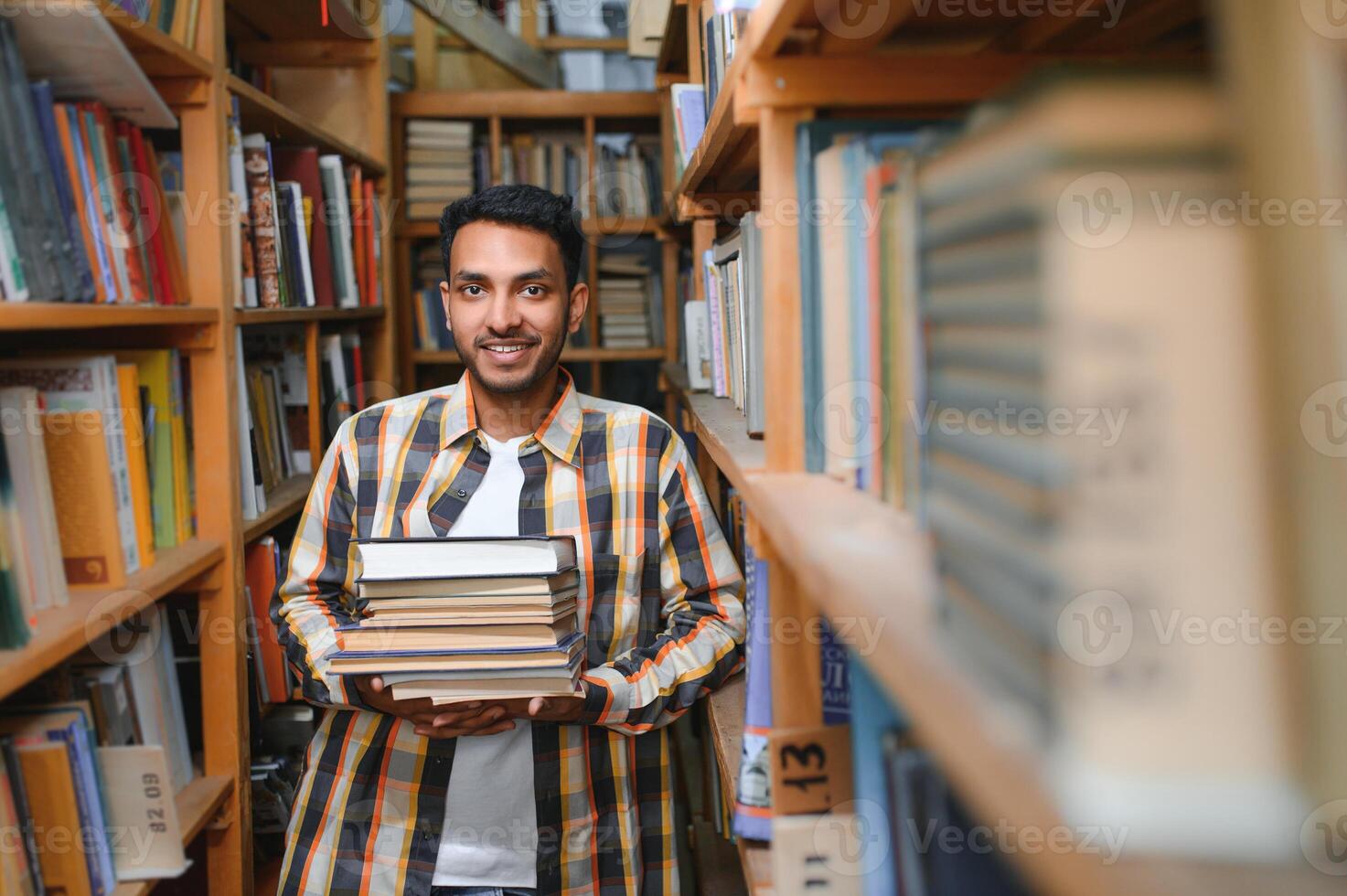 Male indian student at the library with book photo