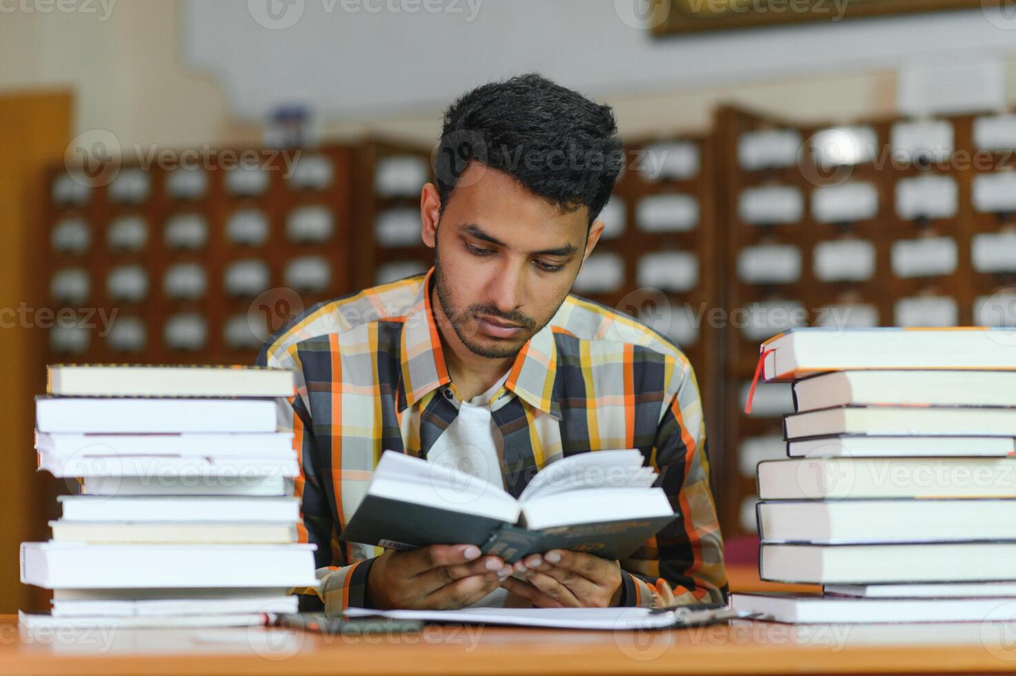 Male indian student at the library with book photo
