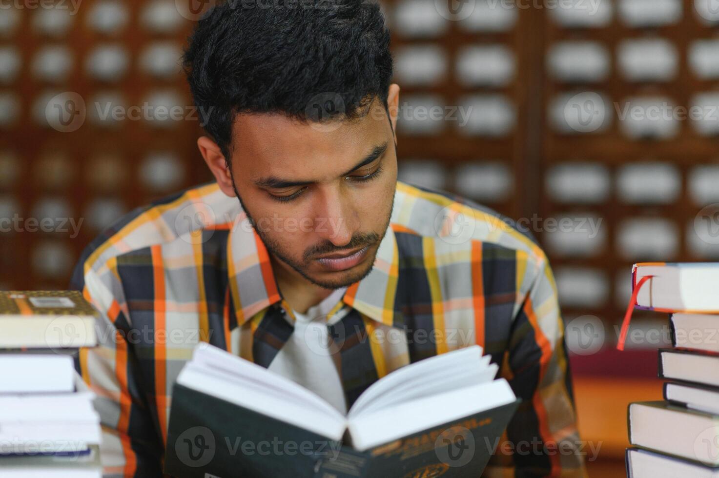 Clever arabian or indian male student or freelancer, in stylish casual clothes in the library photo
