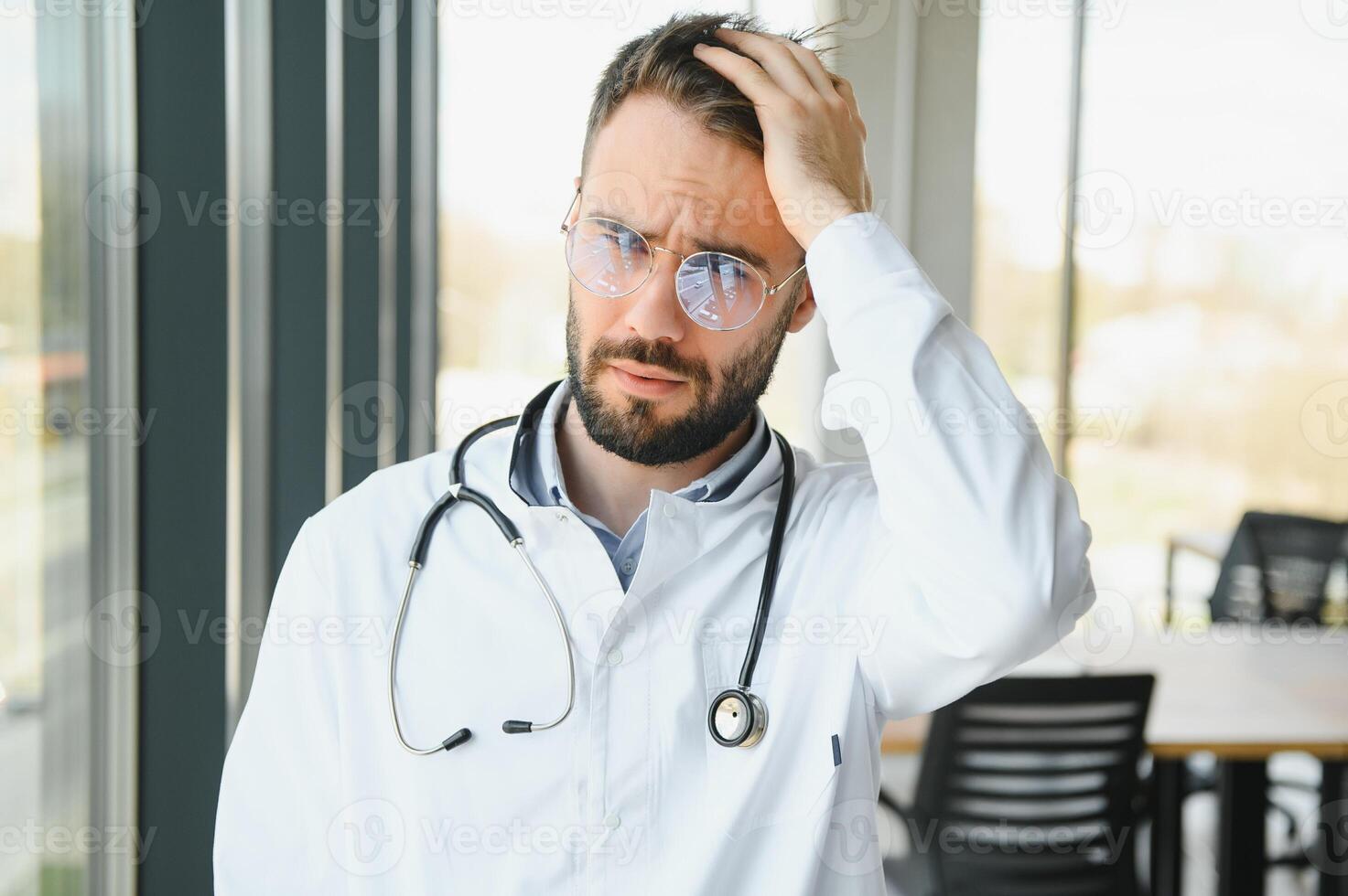 Stressed male doctor. Mid adult male doctor working long hours. Overworked doctor in his office. Not even doctors are exempt from burnout photo