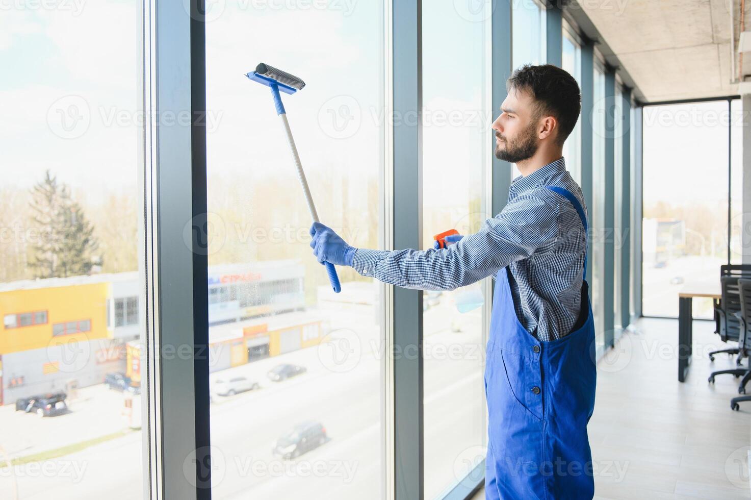 Young indian man washing window in office photo