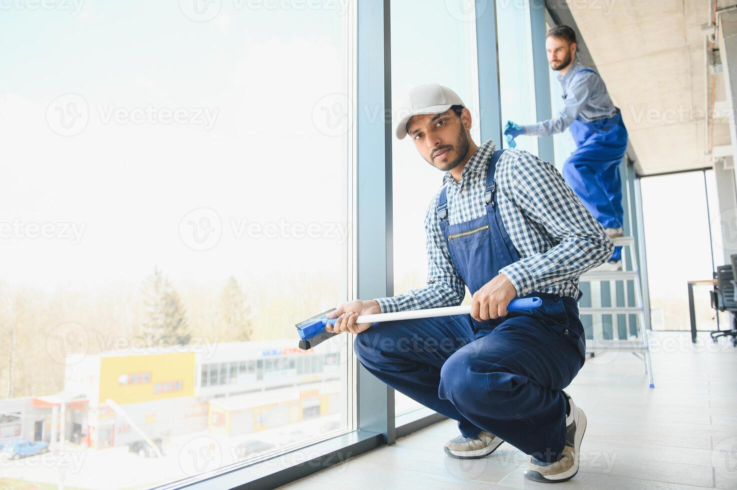 multiethnic professional cleaners in uniform washing large windows in office photo