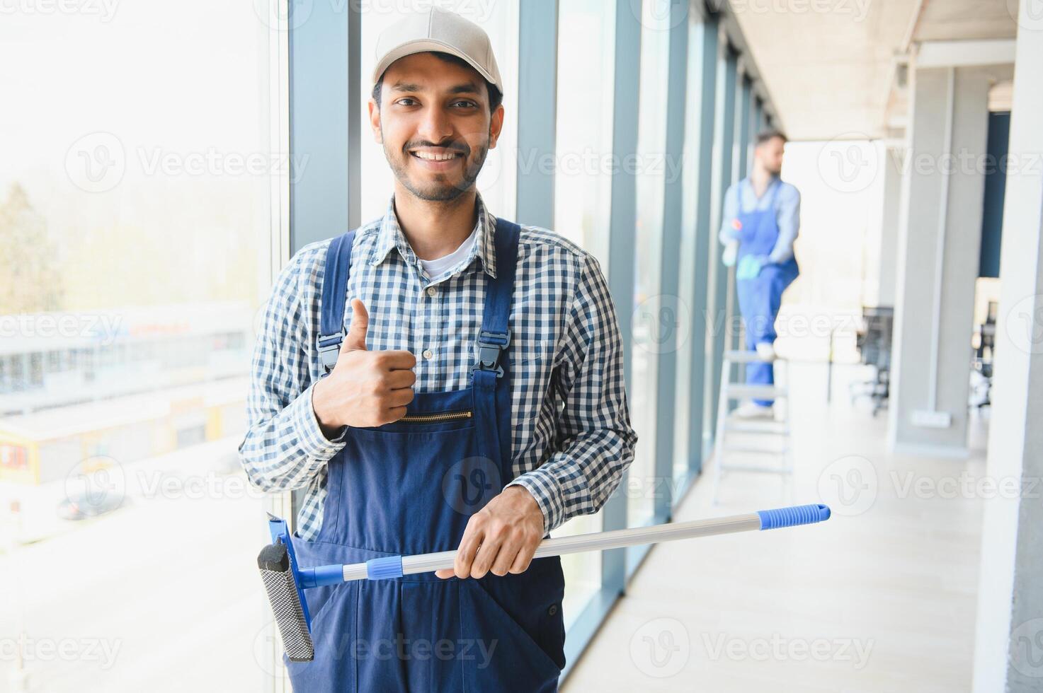 Young indian man washing window in office. photo