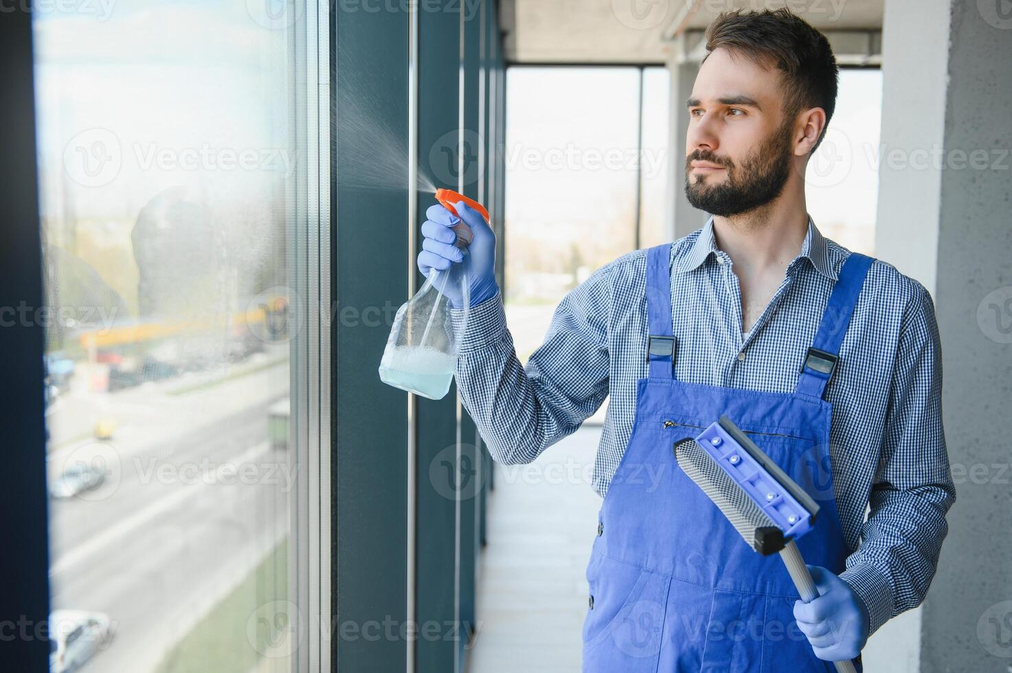 Young man cleaning window in office photo