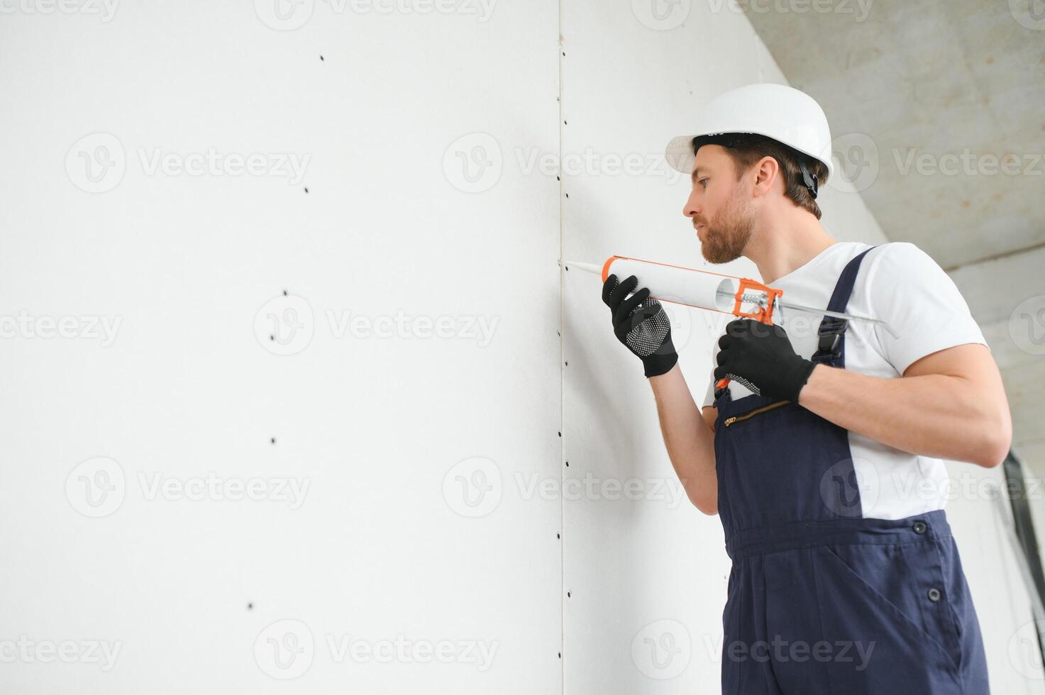 Professional Workman Applying Silicone Sealant With Caulking Gun on the Wall photo