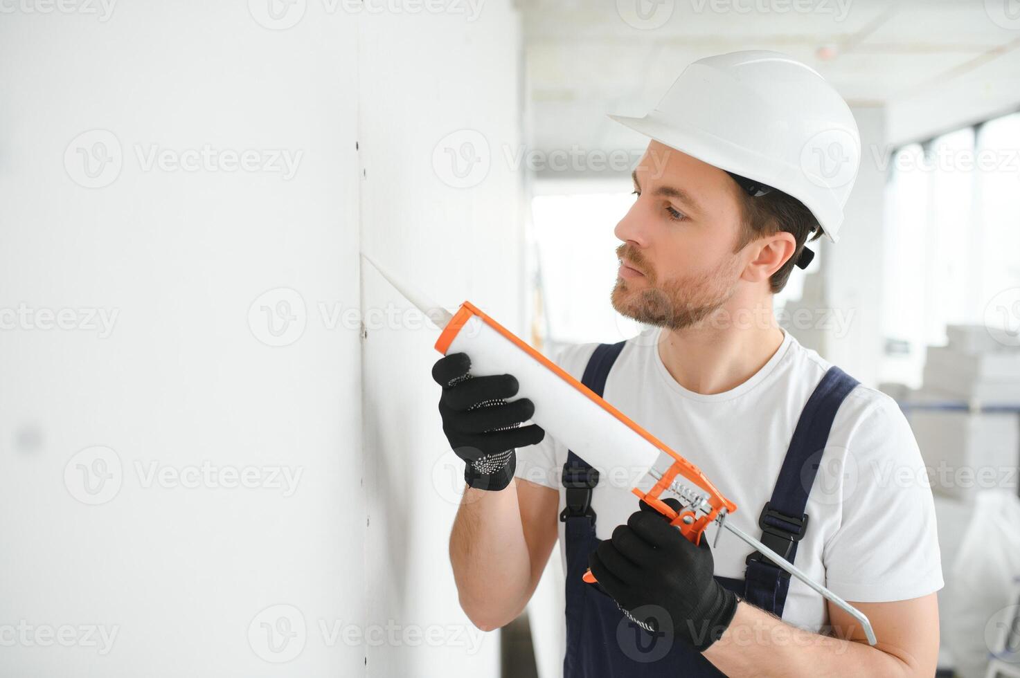Professional Workman Applying Silicone Sealant With Caulking Gun on the Wall photo