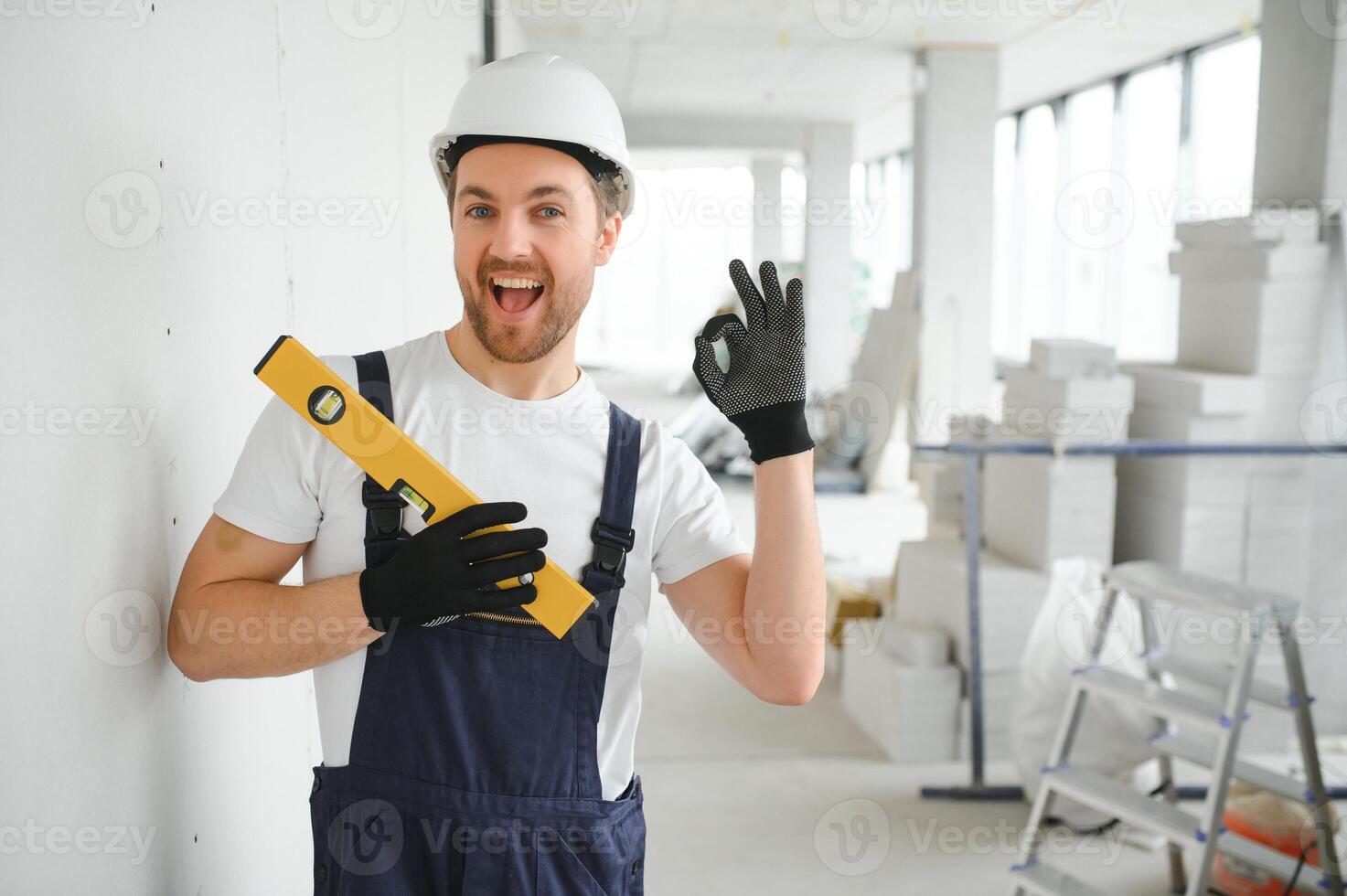 Portrait of positive, handsome young male builder in hard hat. photo