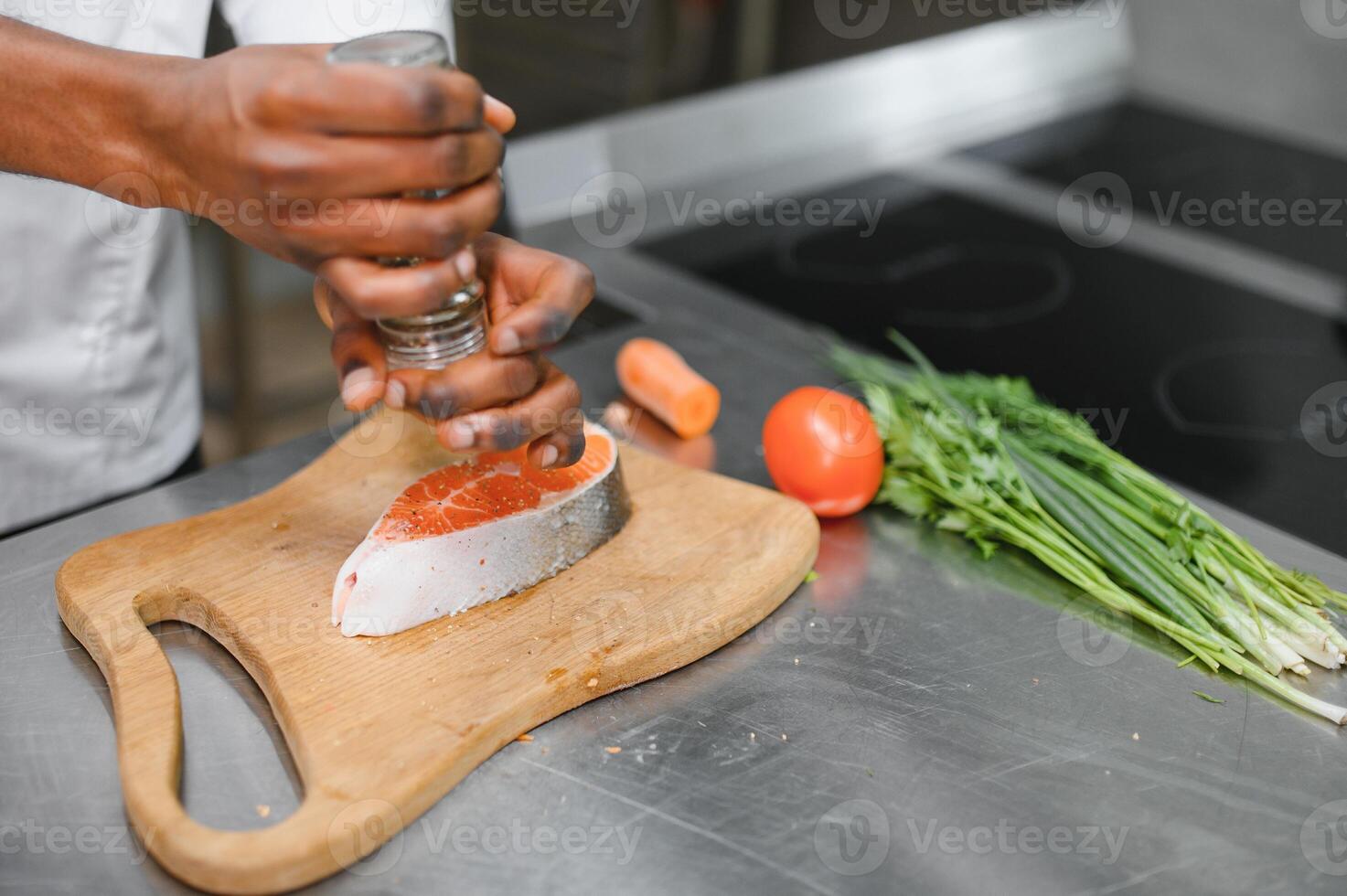 African American male chef preparing salmon fish in restaurant kitchen photo
