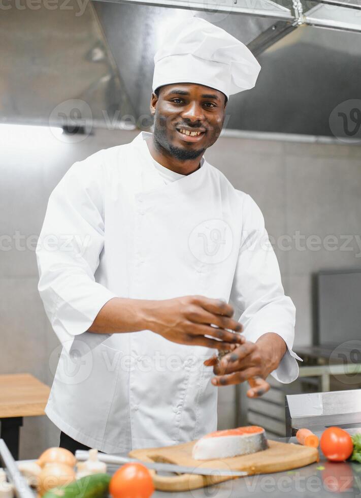 Portrait of happy African American male chef standing in restaurant kitchen photo