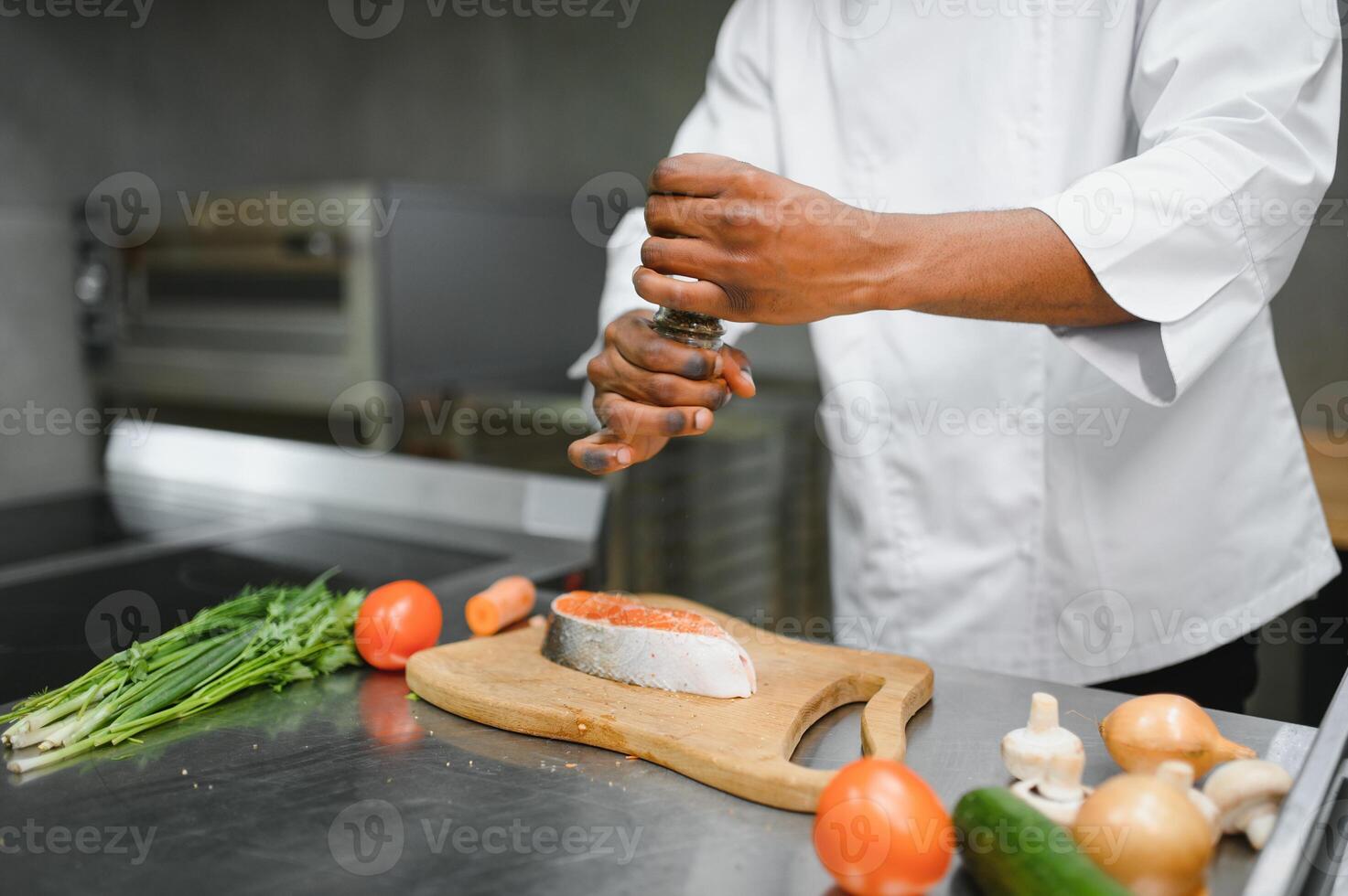 African American male chef preparing salmon fish in restaurant kitchen photo