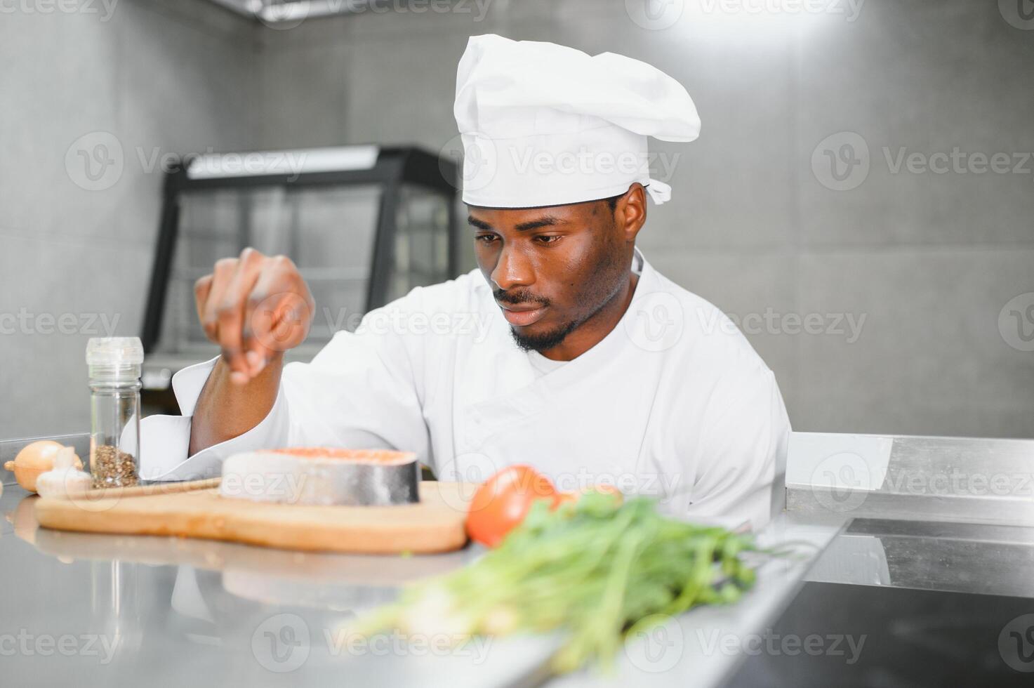 Portrait of happy African American male chef standing in restaurant kitchen photo