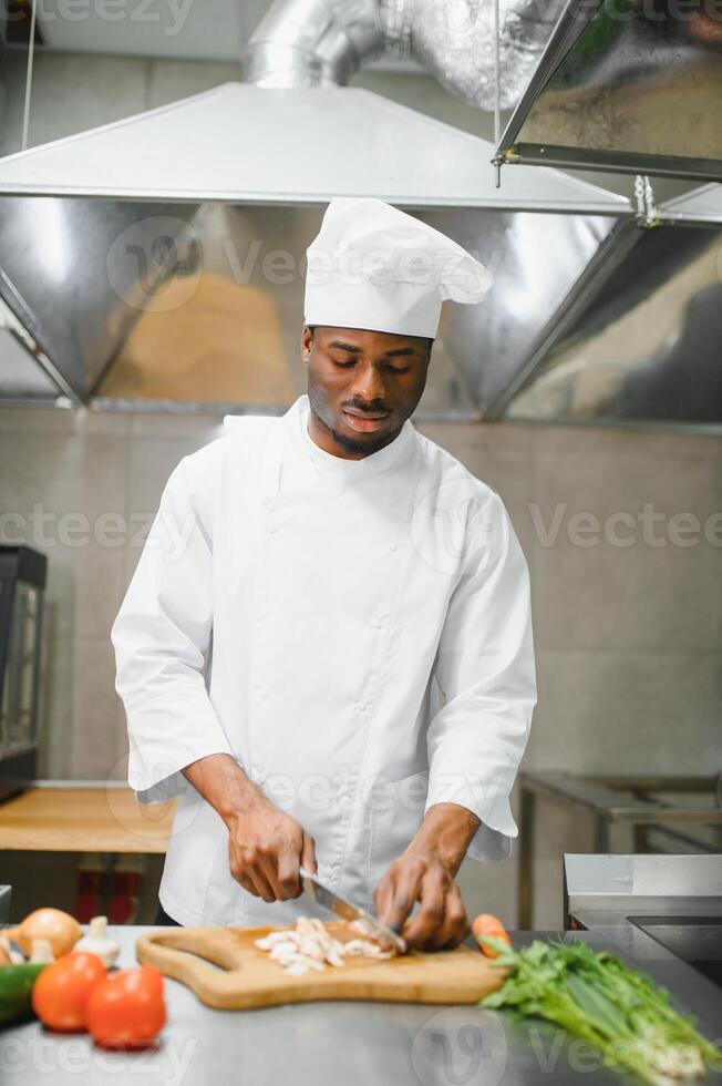 African American male chef standing at kitchen counter in restaurant kitchen, copy space photo