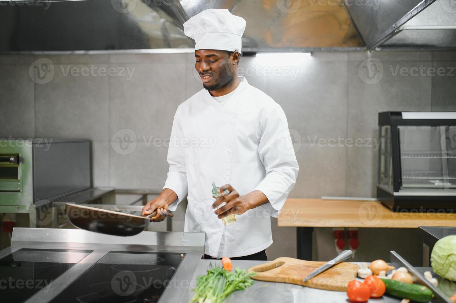Portrait of happy African American male chef standing in restaurant kitchen photo