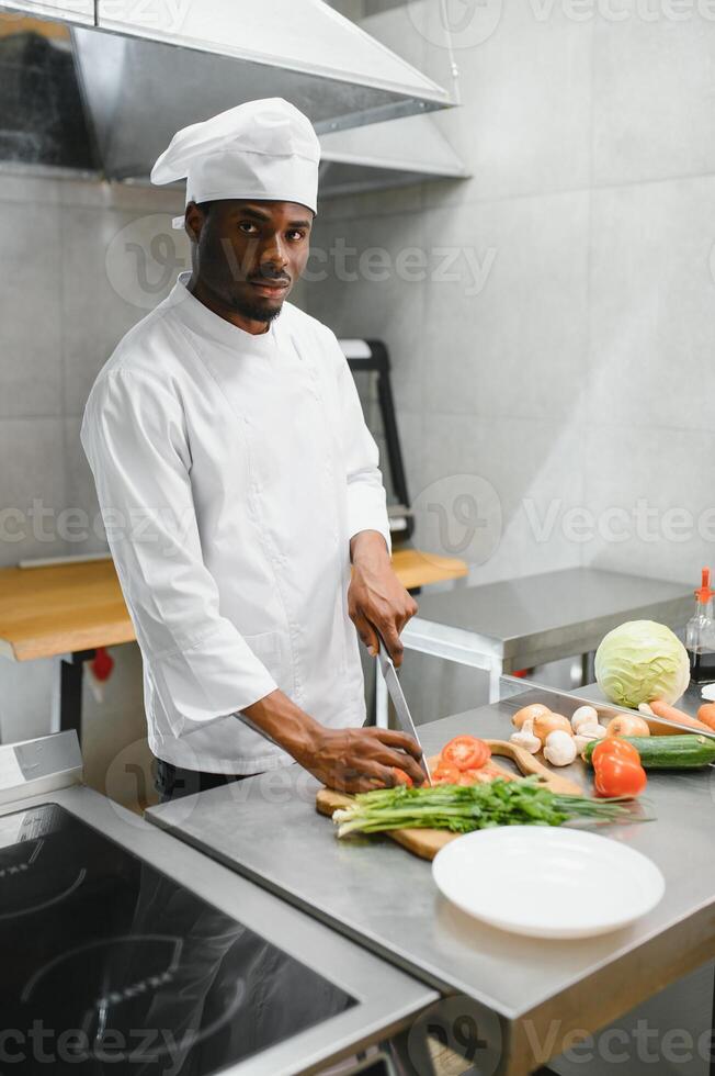 African American male chef standing at kitchen counter in restaurant kitchen, copy space photo