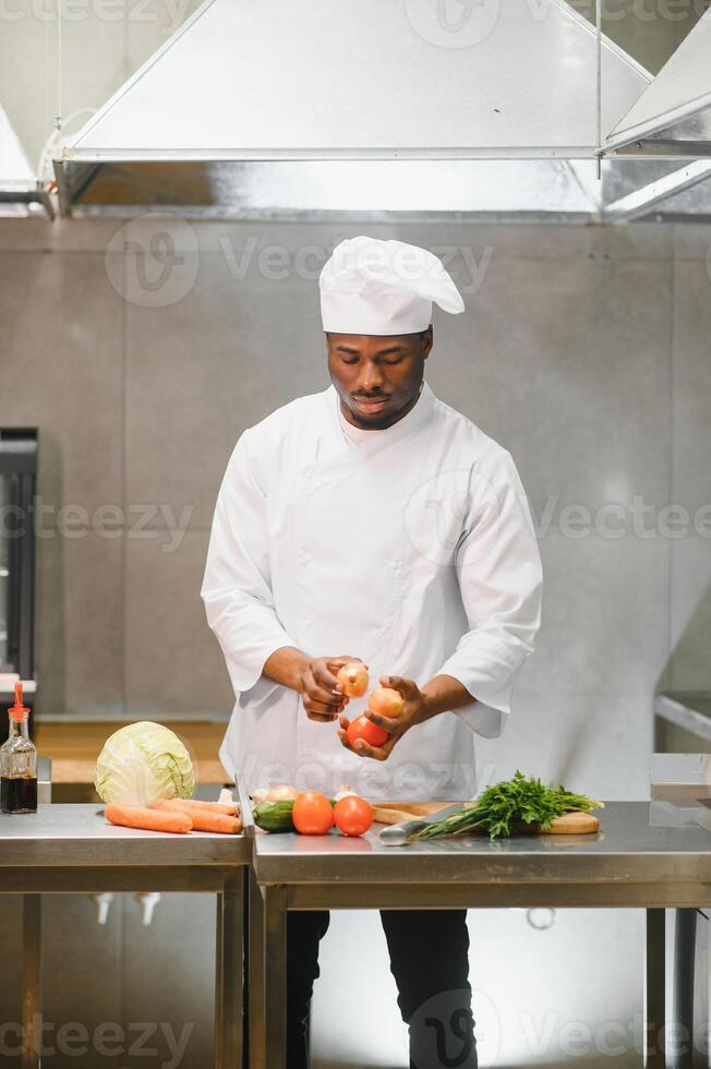 Portrait of happy African American male chef standing in restaurant kitchen photo