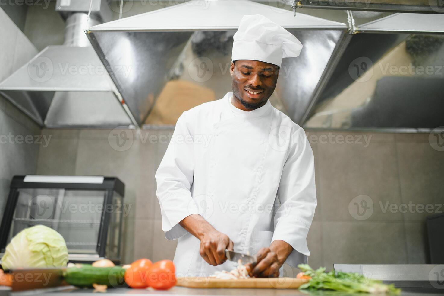 Portrait of happy African American male chef standing in restaurant kitchen photo