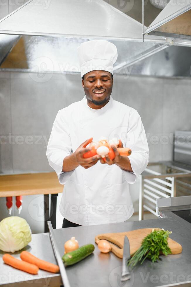 African American chef cooking tasty salad in kitchen photo