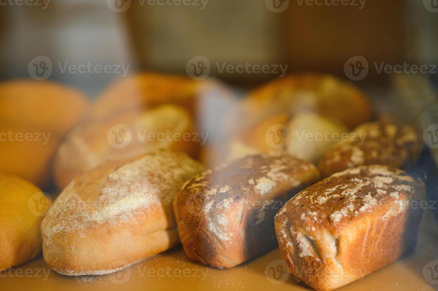 Freshly baked bread on bakery shelves. Bread diversity in bright light. Breads with a golden crust on wooden shelves photo