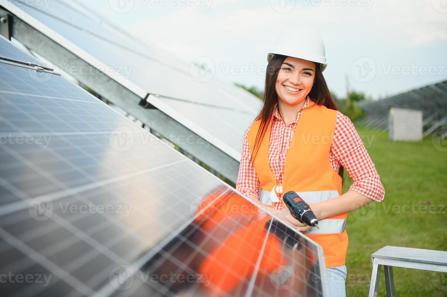 Beautiful young woman near solar panels outdoors photo