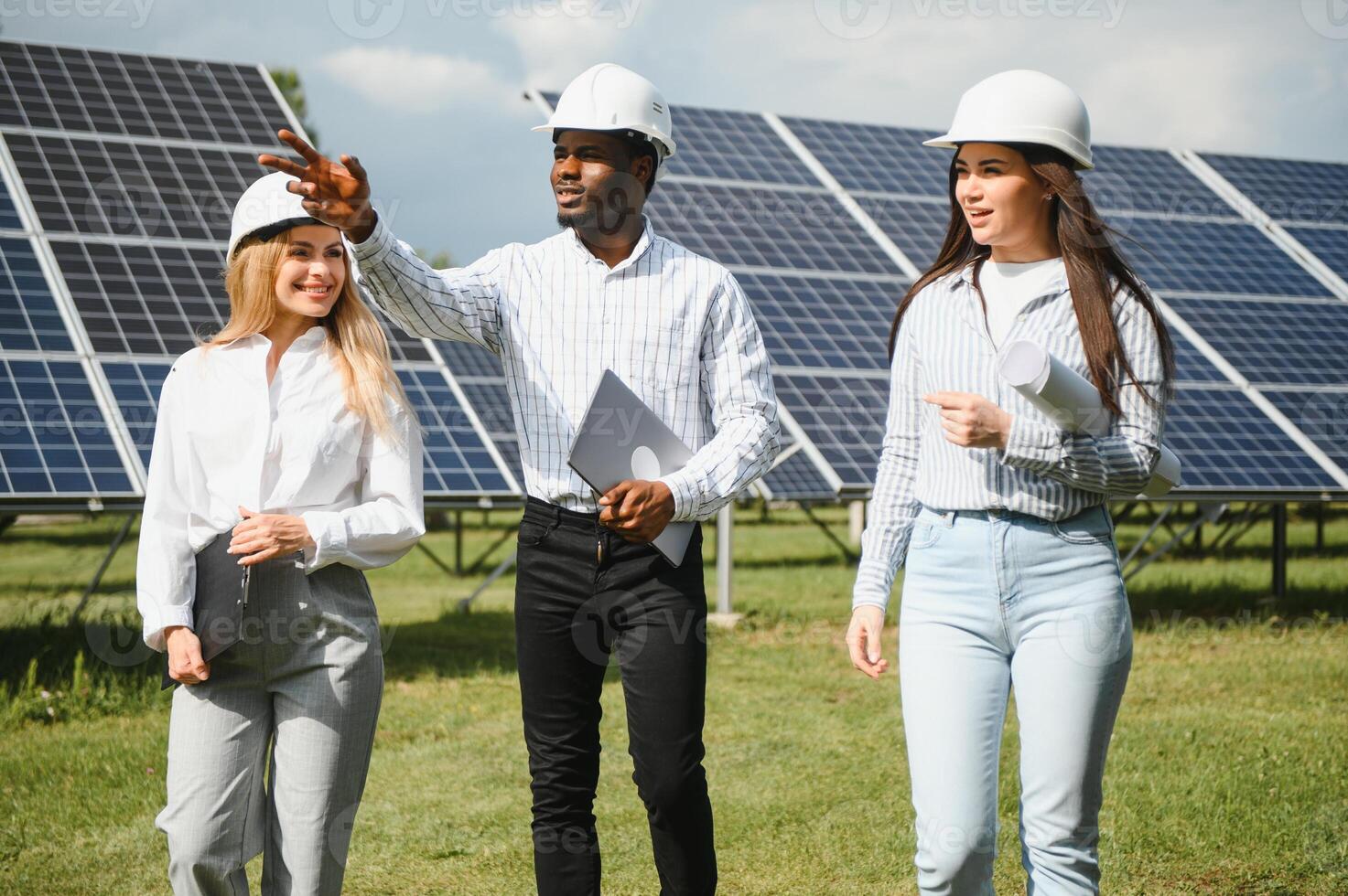 Portrait of engineers standing outside near solar panels. Three workers, two woman and one men photo