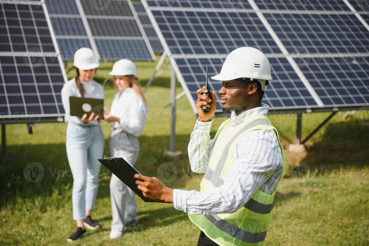 Portrait of engineers standing outside near solar panels. Three workers, two woman and one men photo