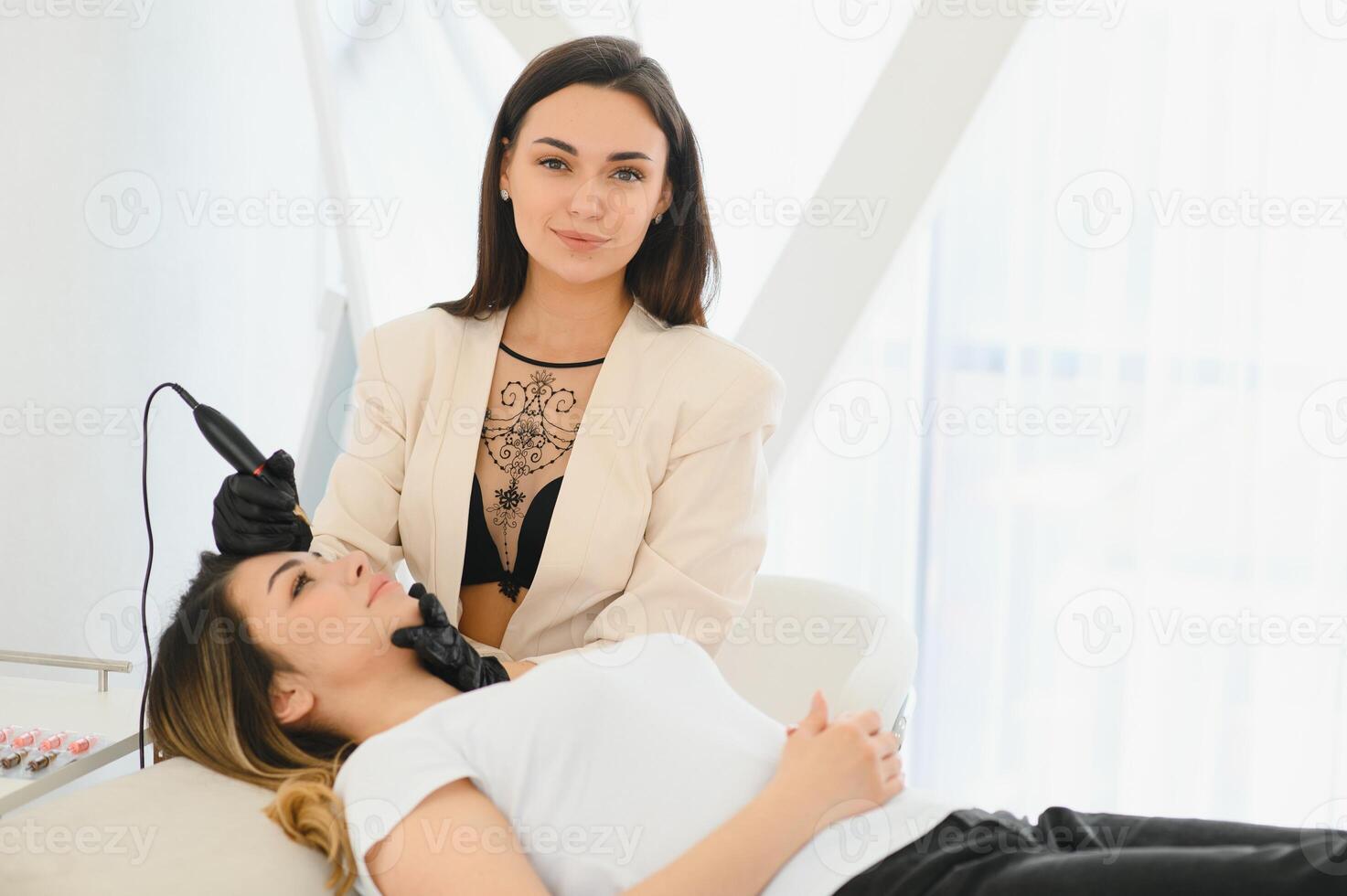 Cosmetologist applying permanent make up on eyebrows- eyebrow tattoo photo