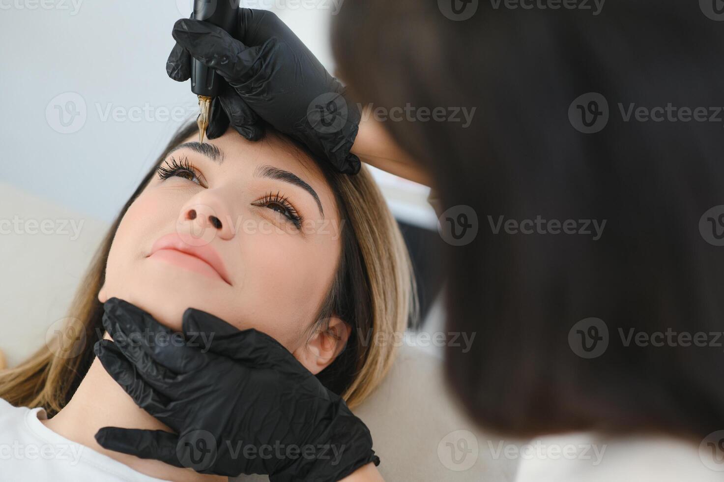 Young woman during procedure of permanent eyebrow makeup photo