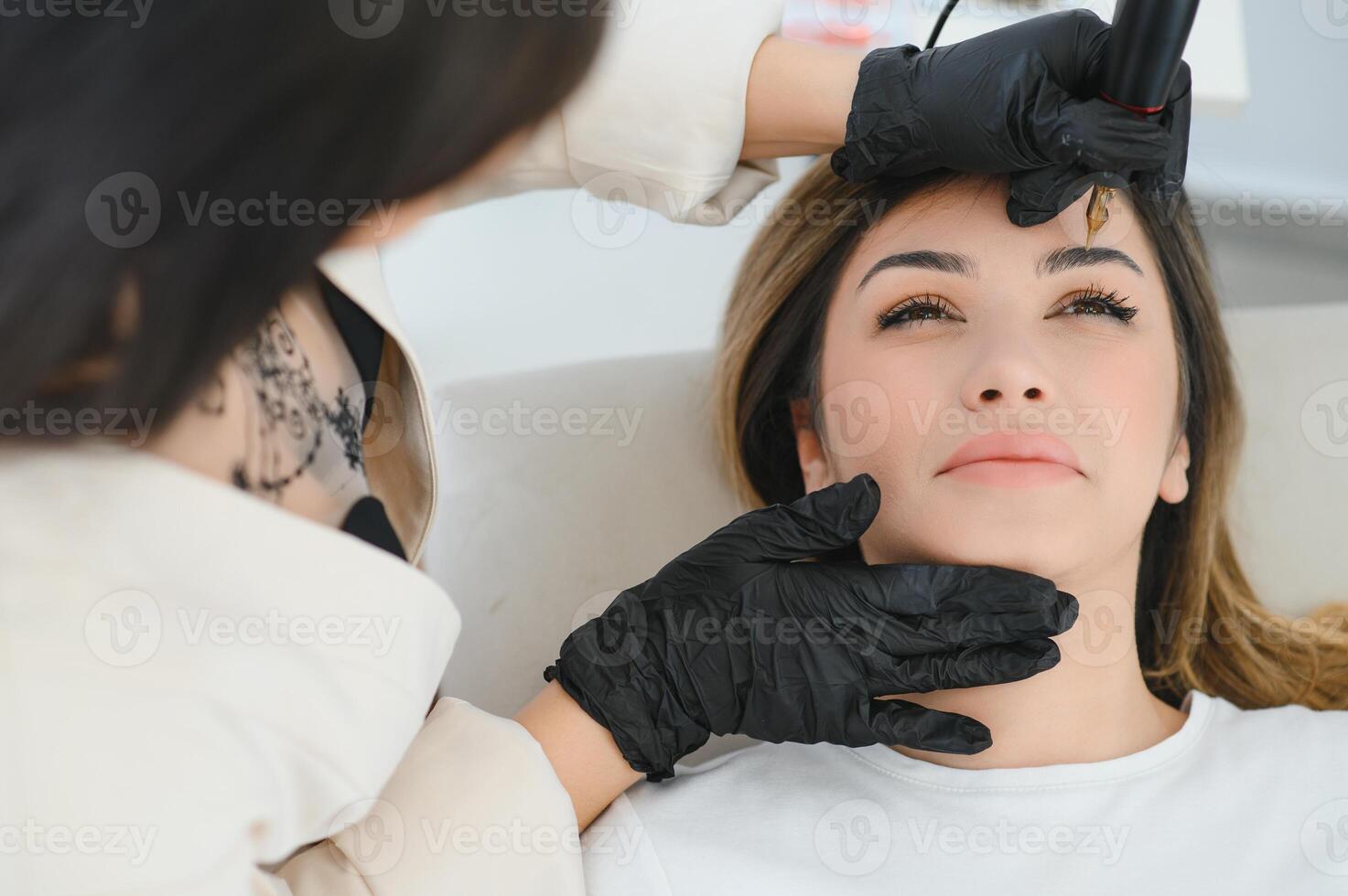 Young woman during procedure of permanent eyebrow makeup photo