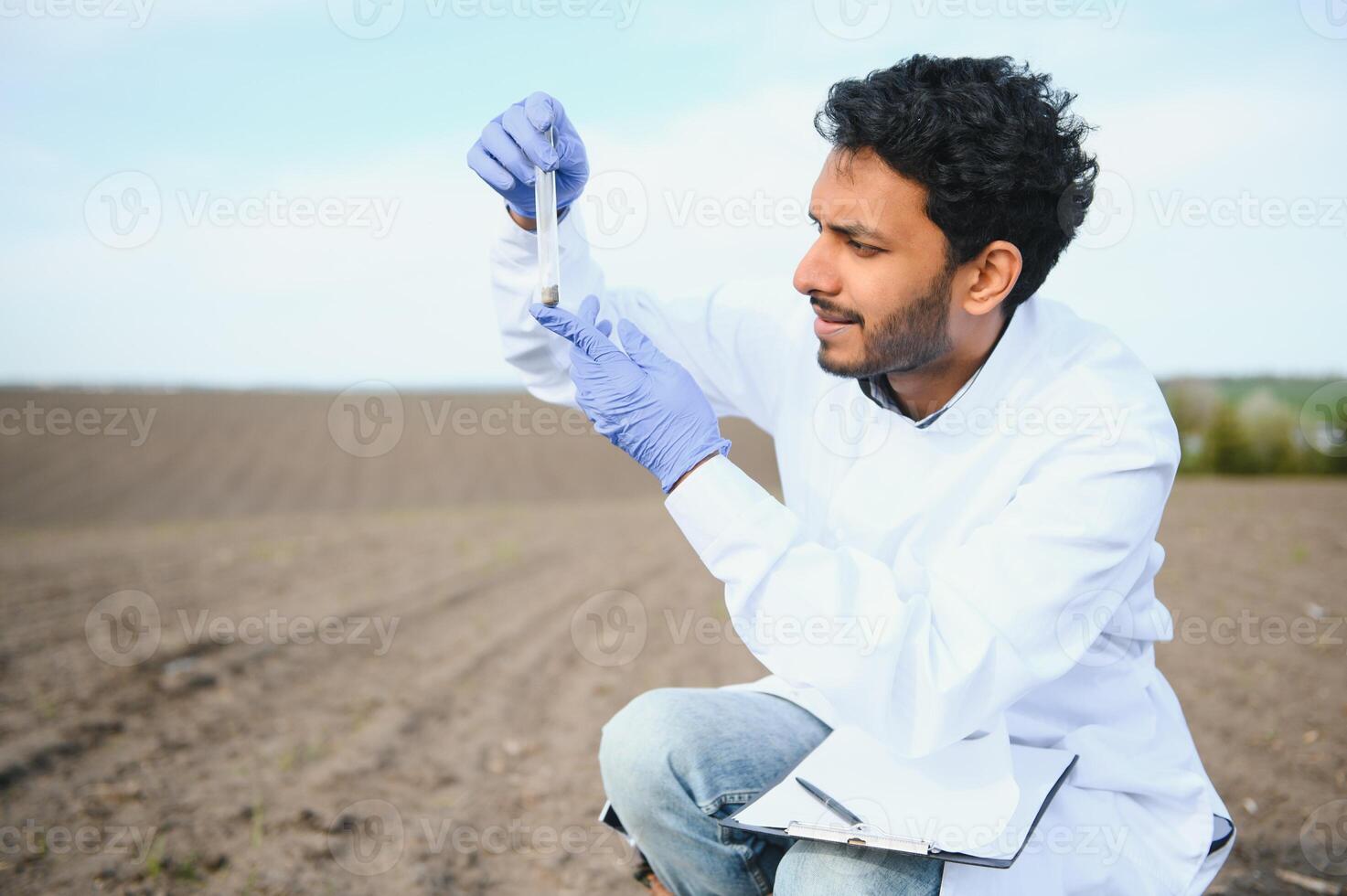 Soil Testing. Indian Agronomy Specialist taking soil sample for fertility analysis. Hands in gloves close up. Environmental protection, organic soil certification, field work, research photo