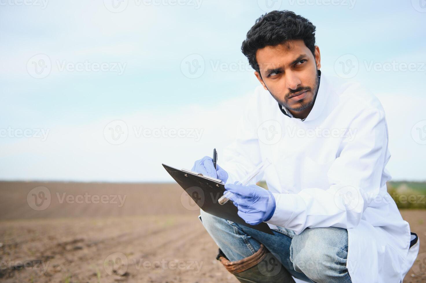 Soil Testing. Indian Agronomy Specialist taking soil sample for fertility analysis. Hands in gloves close up. Environmental protection, organic soil certification, field work, research photo