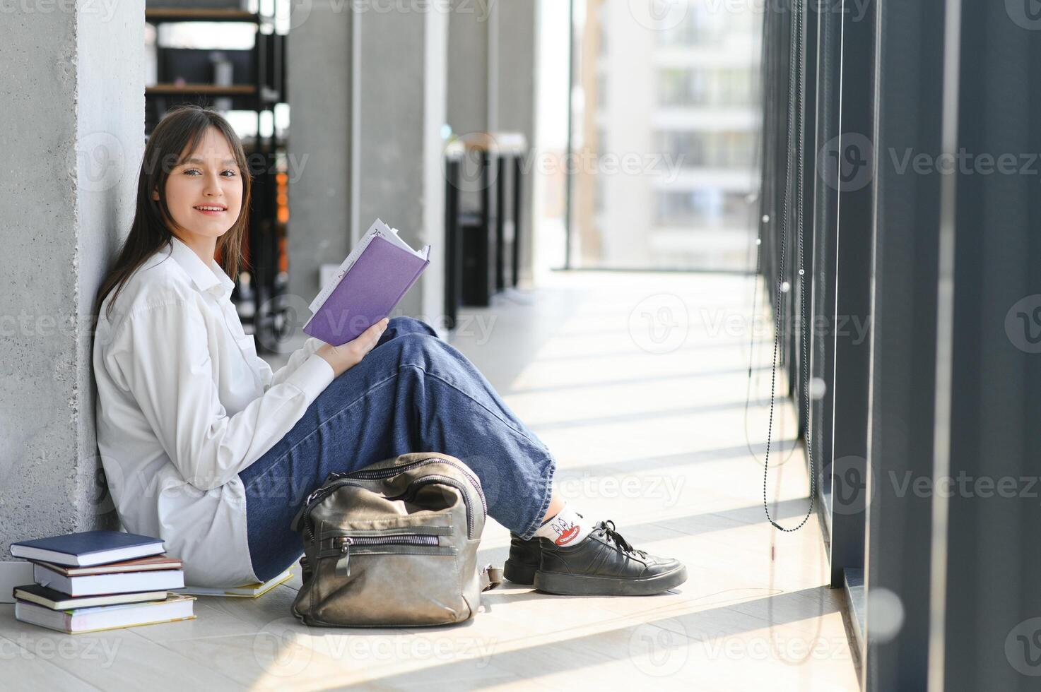 Educational concept. A modern girl student sits on the floor and reading joyfully a book. Modern generation. Reading. photo