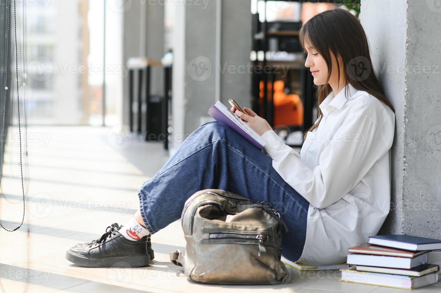 Educational concept. A modern girl student sits on the floor and reading joyfully a book. Modern generation. Reading. photo