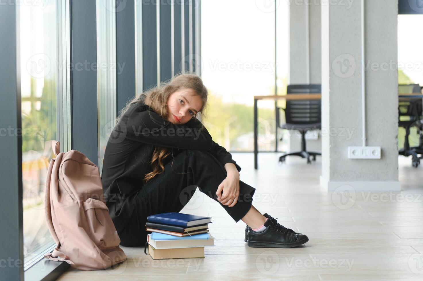 Lonely sad schoolgirl while all her classmates ignored her. Social exclusion problem. Bullying at school concept. photo