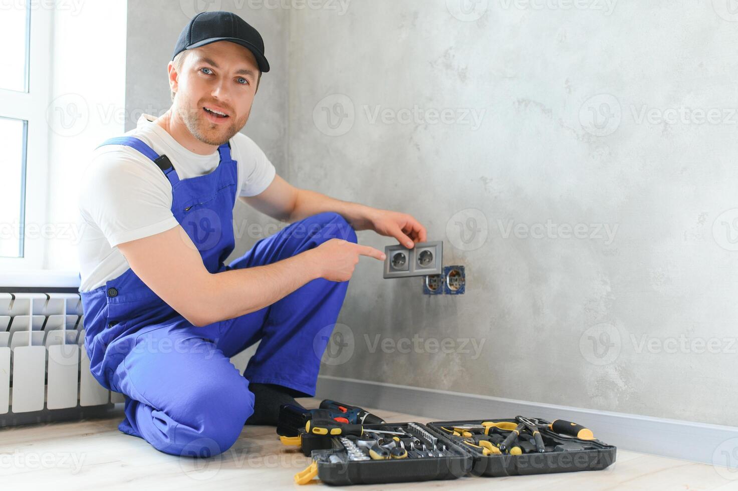 Construction worker electrician assembles an electrical outlet in an apartment photo