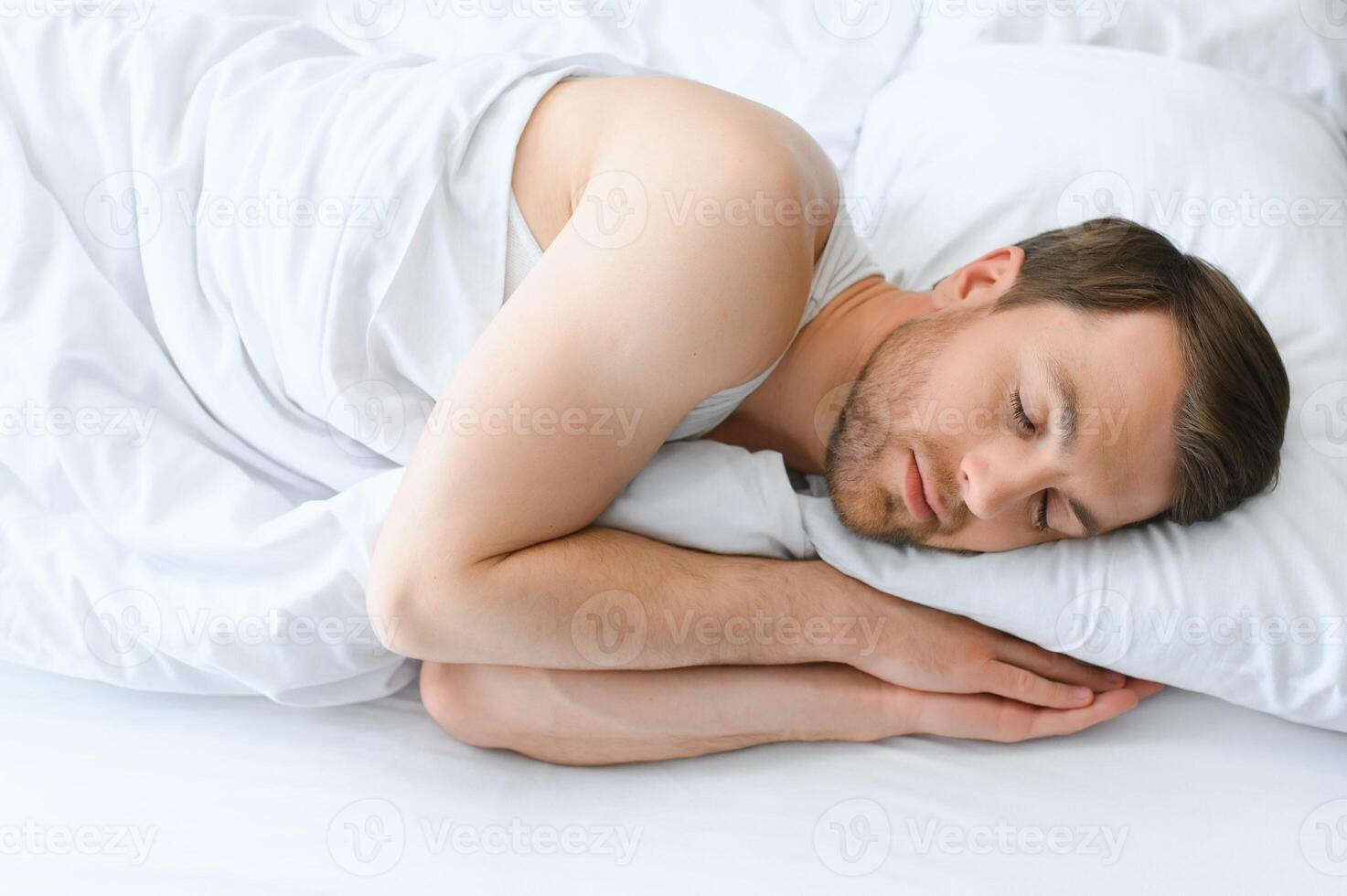 Handsome man sleeping under soft blanket in bed at home photo