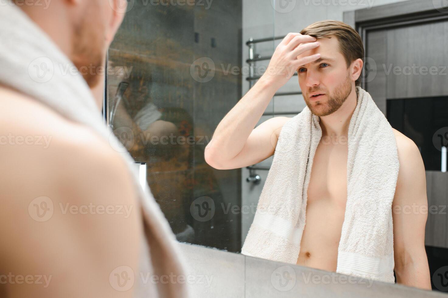 Young man looking in mirror after shaving at home photo