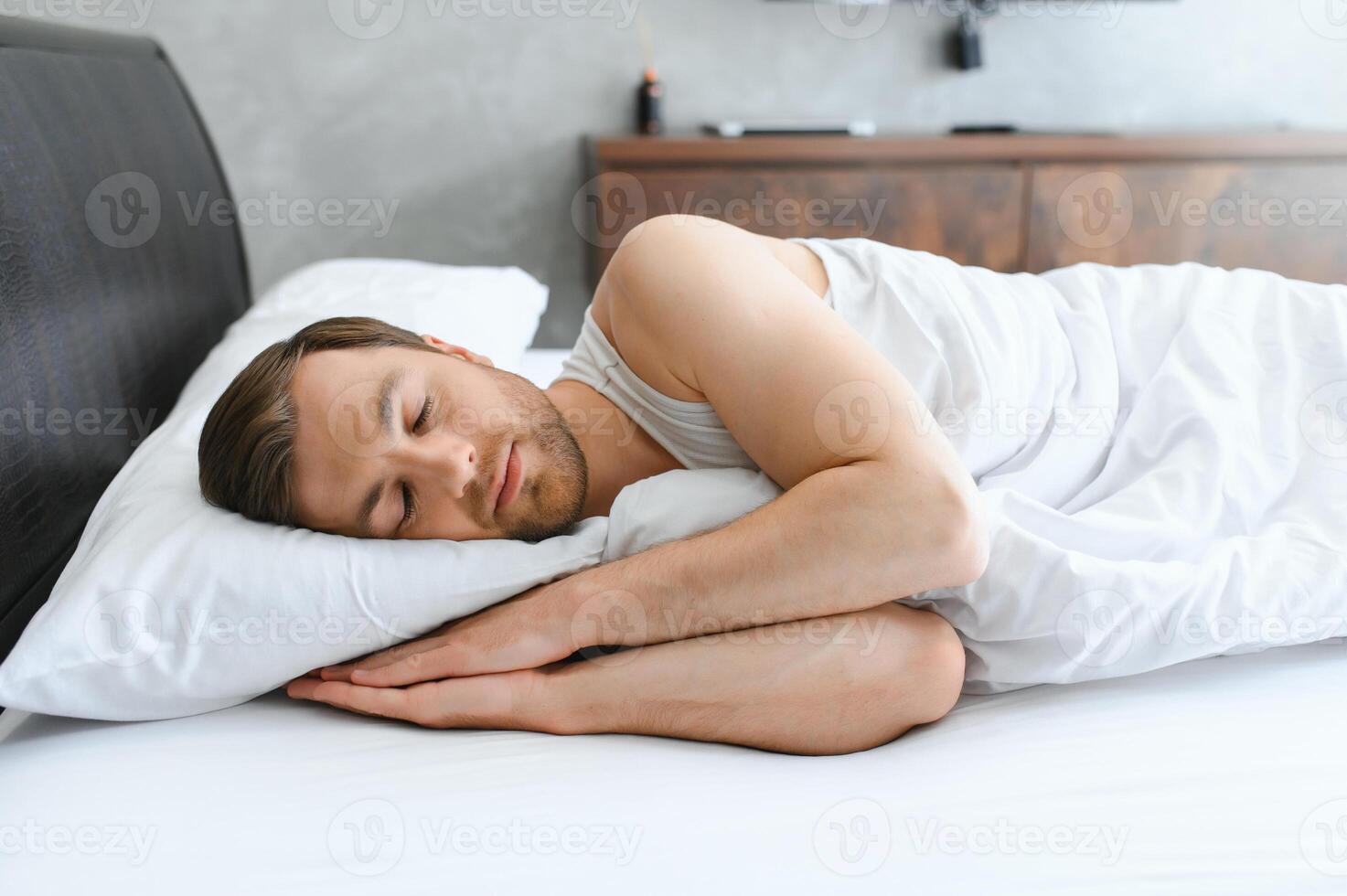 Handsome man sleeping under soft blanket in bed at home photo