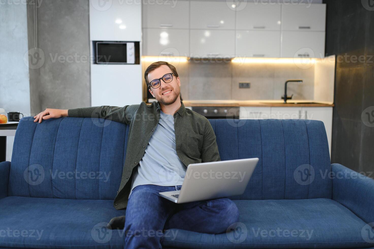 Side view handsome young businessman in eyewear working with computer. Pleasant happy man communicating in social network, searching information online photo