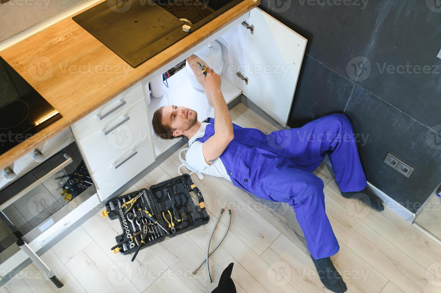 Young plumber or technician installing or repairing system of water filtration photo