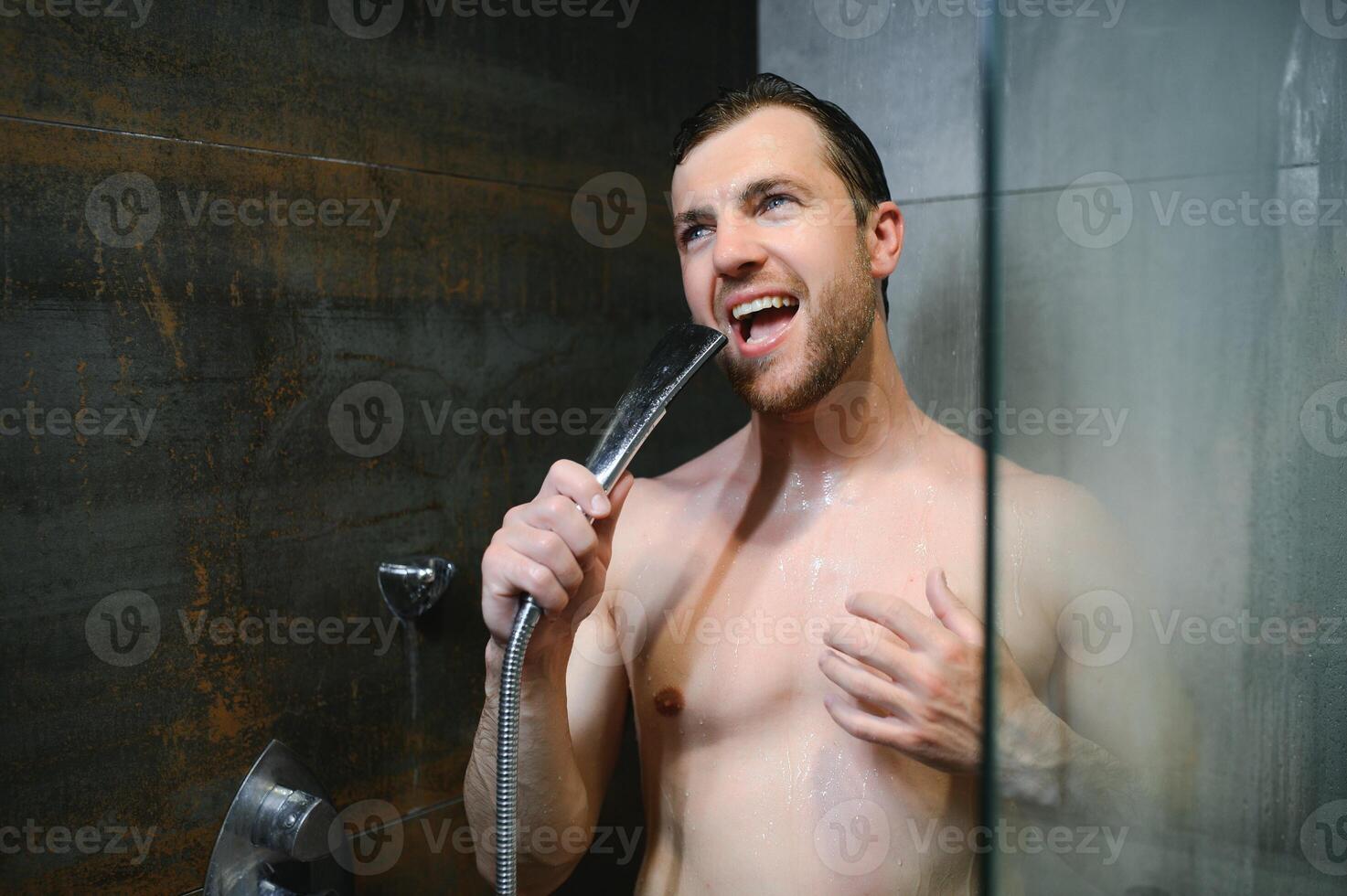 Young single handsome caucasian man are taking shower in the bathroom, he is singing, happy and relaxed. photo