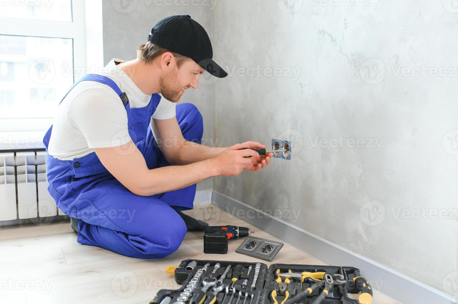 Construction worker electrician assembles an electrical outlet in an apartment photo