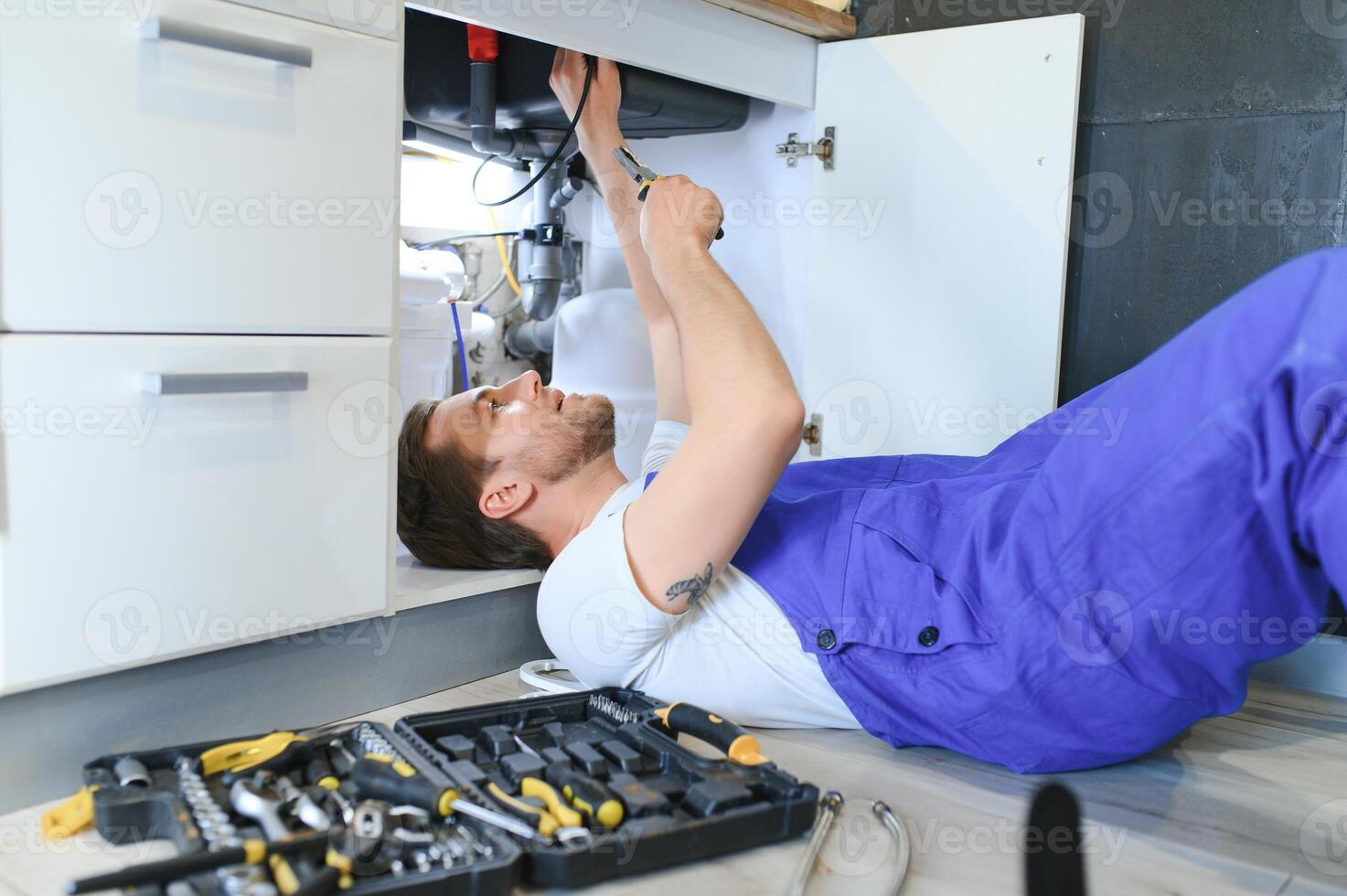 Plumber installs or change water filter. Replacement aqua filter. Repairman installing water filter cartridges in a kitchen. Installation of reverse osmosis water purification system. photo
